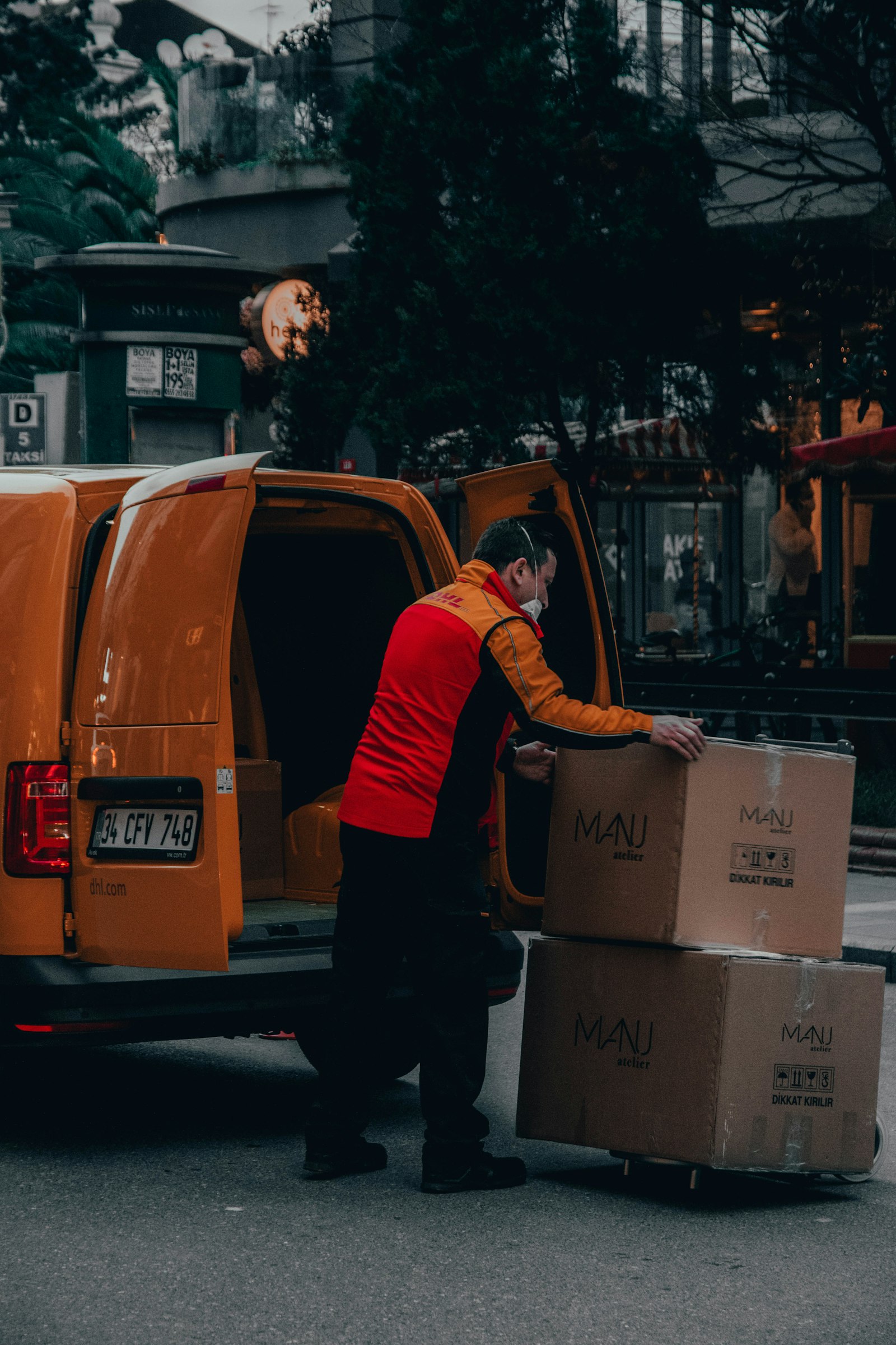 Delivery driver loading large boxes into an orange van